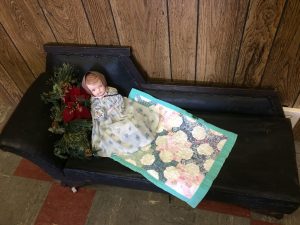 Vintage doll lying on a miniature fainting couch